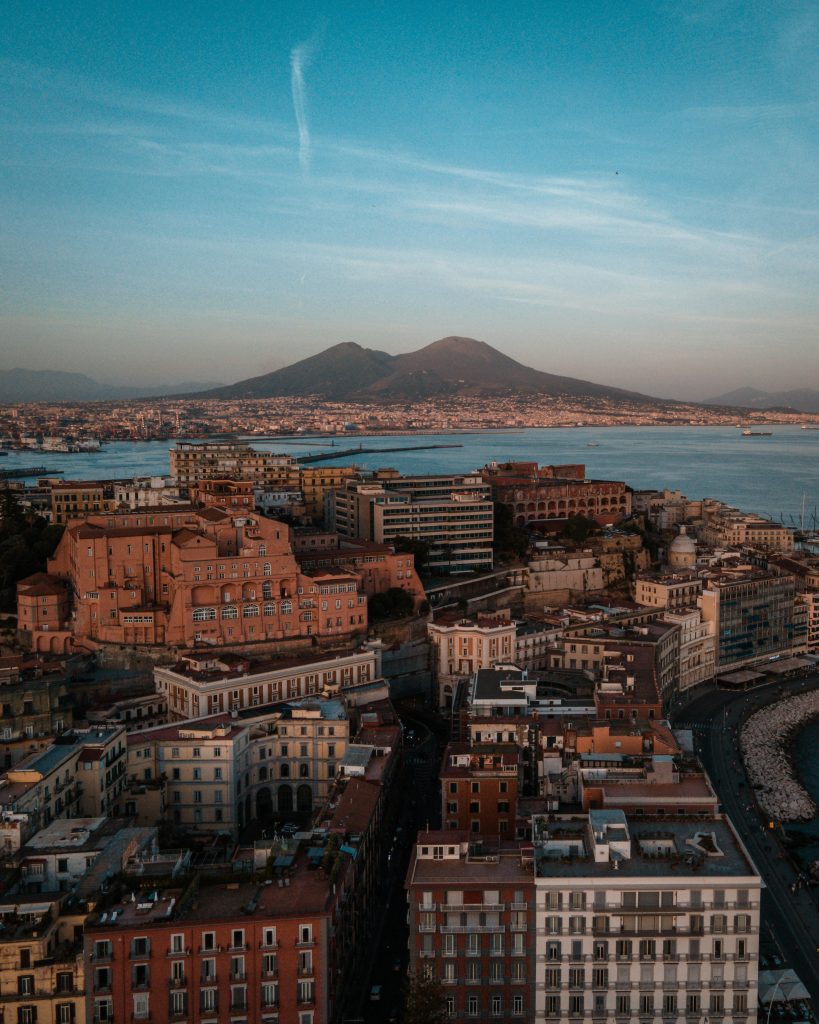 Stunning aerial view of Naples, Italy, with Mount Vesuvius in the background during sunset.