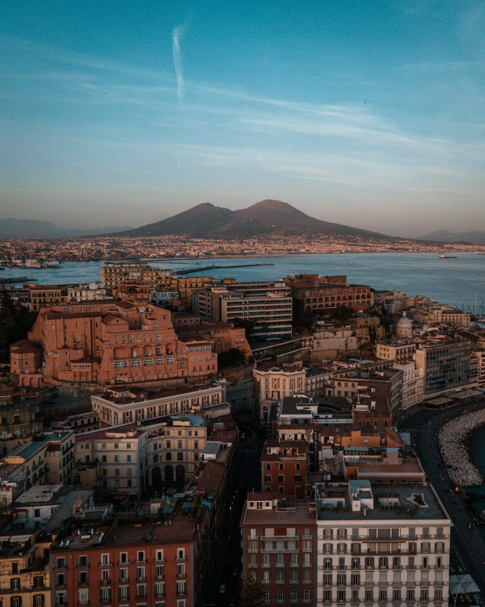 Stunning aerial view of Naples, Italy, with Mount Vesuvius in the background during sunset.